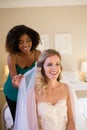 Beautician adjusting veil of bride hair while sitting on bed at home