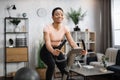 Smiling beautiful african american sports woman in sportswear cycling bike at home Royalty Free Stock Photo