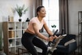 Smiling beautiful african american sports woman in sportswear cycling bike at home Royalty Free Stock Photo