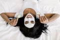 Smiling beautiful African woman in white t-shirt, with facial mud clay mask on her face holding cucumber slices in her Royalty Free Stock Photo