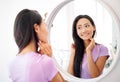 Smiling beautiful asian woman looking at herself in the mirror at home