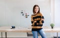 Smiling beautiful Asian woman photographer standing with arms crossed and looking away while work selecting best photos after