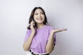 Smiling beautiful Asian woman pointing finger sideward to space while picking up phone call isolated white background