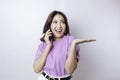 Smiling beautiful Asian woman pointing finger sideward to space while picking up phone call isolated white background