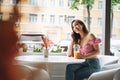 Smiling beautiful asian young woman with long hair talking on mobile phone on the terrace of summer cafe Royalty Free Stock Photo