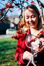Smiling beautiful blond woman stands with a glass of wine in the sun on the background of rowan branches. Autumn Royalty Free Stock Photo