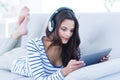 Smiling beautiful brunette listening music while using her tablet Royalty Free Stock Photo