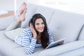 Smiling beautiful brunette listening music while using her tablet Royalty Free Stock Photo