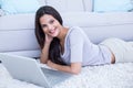 Smiling beautiful brunette lying on the floor and using her laptop Royalty Free Stock Photo