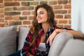 Smiling beautiful brunette relaxing on the couch and looking at camera in the living room Royalty Free Stock Photo