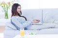 Smiling beautiful brunette relaxing on the couch and using her laptop Royalty Free Stock Photo
