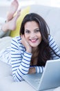 Smiling beautiful brunette relaxing on the couch and using her laptop Royalty Free Stock Photo