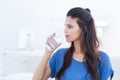 Smiling beautiful brunette sitting on the couch and drinking water Royalty Free Stock Photo