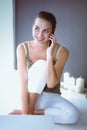 Smiling beautiful brunette sitting on the floor and using her phone in the living room Royalty Free Stock Photo