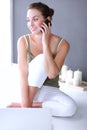 Smiling beautiful brunette sitting on the floor and using her phone in the living room Royalty Free Stock Photo