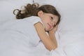 Smiling beautiful child girl lying on a pillow, white bed, close-up face Royalty Free Stock Photo