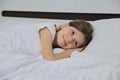 Smiling beautiful child girl lying on a pillow, white bed, close-up face Royalty Free Stock Photo