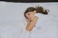 Smiling beautiful child girl lying on a pillow, white bed, close-up face Royalty Free Stock Photo