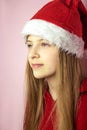 Smiling beautiful girl with long hair in fluffy Santa Claus hat on a pink background. Royalty Free Stock Photo