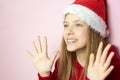 Smiling beautiful girl with long hair in fluffy Santa Claus hat on a pink background Royalty Free Stock Photo