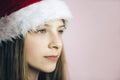 Smiling beautiful girl with long hair in fluffy Santa Claus hat on a pink background. Royalty Free Stock Photo