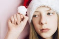 Smiling beautiful girl with long hair in fluffy Santa Claus hat on a pink background. Royalty Free Stock Photo