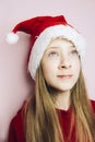 Smiling beautiful girl with long hair in fluffy Santa Claus hat on a pink background. Royalty Free Stock Photo