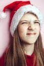 Smiling beautiful girl with long hair in fluffy Santa Claus hat on a pink background. Royalty Free Stock Photo