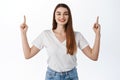 Smiling beautiful girl proudly showing advertisement, pointing fingers up at top promo deal, show discounts shop Royalty Free Stock Photo