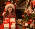 Smiling beautiful girl in santa hat gives a box with a gift on the background of the christmas room.Christmas mood Royalty Free Stock Photo