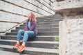 Portrait of smiling Beautiful modern young female teenager with extraordinary hairstyle color in checkered sitting on the old town