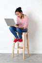 Smiling beautiful multi-ethnic girl sitting on stool with computer Royalty Free Stock Photo