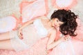 Smiling beautiful pregnant brunette girl in soft peach pillows Royalty Free Stock Photo