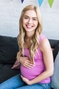 smiling beautiful pregnant woman sitting on sofa Royalty Free Stock Photo