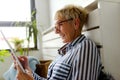 Smiling beautiful senior woman using digital tablet at home Royalty Free Stock Photo