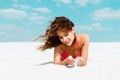 Beautiful sexy girl in swimsuit lying on sandy beach with blue sky and clouds at background Royalty Free Stock Photo