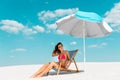 Beautiful sexy girl in swimsuit and sunglasses sitting in deck chair under umbrella on sandy beach Royalty Free Stock Photo