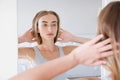 Smiling beautiful young woman looking into a mirror at herself in room. Beauty, hygiene, morning and people concept Royalty Free Stock Photo