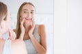 Smiling beautiful young woman looking into a mirror at herself in room. Beauty, hygiene, morning and people concept Royalty Free Stock Photo