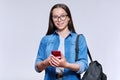 Teenage student with backpack smartphone looking at camera on light ackground Royalty Free Stock Photo