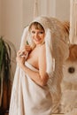 a smiling beautiful woman in a blanket in an Indian headdress of white feathers Royalty Free Stock Photo