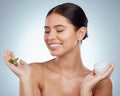 Smiling beautiful woman holding aloe vera leaf for her skincare routine. Caucasian model isolated against grey studio Royalty Free Stock Photo