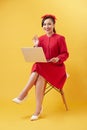 Smiling beautiful woman portrait with laptop on yellow background