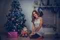 Smiling beautiful woman sitting at home near christmas tree lights background. Christmas and relaxation concept Royalty Free Stock Photo