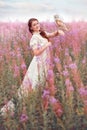 Smiling beautiful woman with owl at field of pink flowers