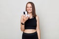 Smiling beautiful woman wearing black top standing isolated over white background using her mobile phone browsing internet Royalty Free Stock Photo