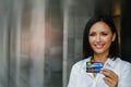 Smiling, beautiful woman worker holds a credit card for shopping instead of convenient cash. Royalty Free Stock Photo