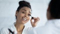 Smiling beautiful young african american woman applying mascara. Royalty Free Stock Photo