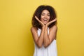 Smiling beautiful young African American woman in white T-shirt posing with hands on chin. Studio shot on Yellow Royalty Free Stock Photo