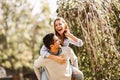 Beautiful young couple in love having fun in park. Handsome man giving piggy back to his girlfriend Royalty Free Stock Photo